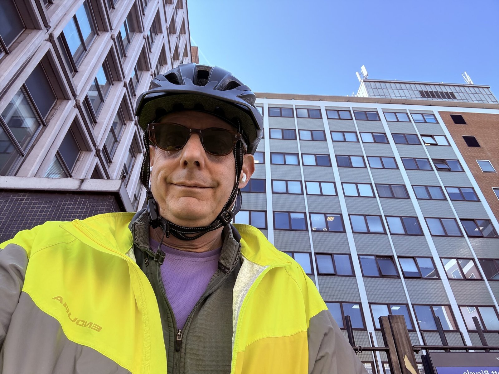 IMG_1047.jpeg Man wearing cycling gear in front of a tall building